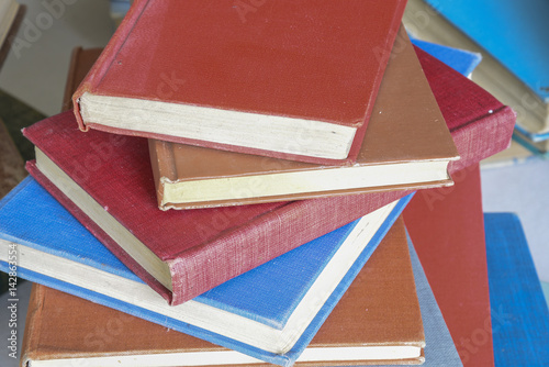 Cloth hardcover books piled randomly on a table photo