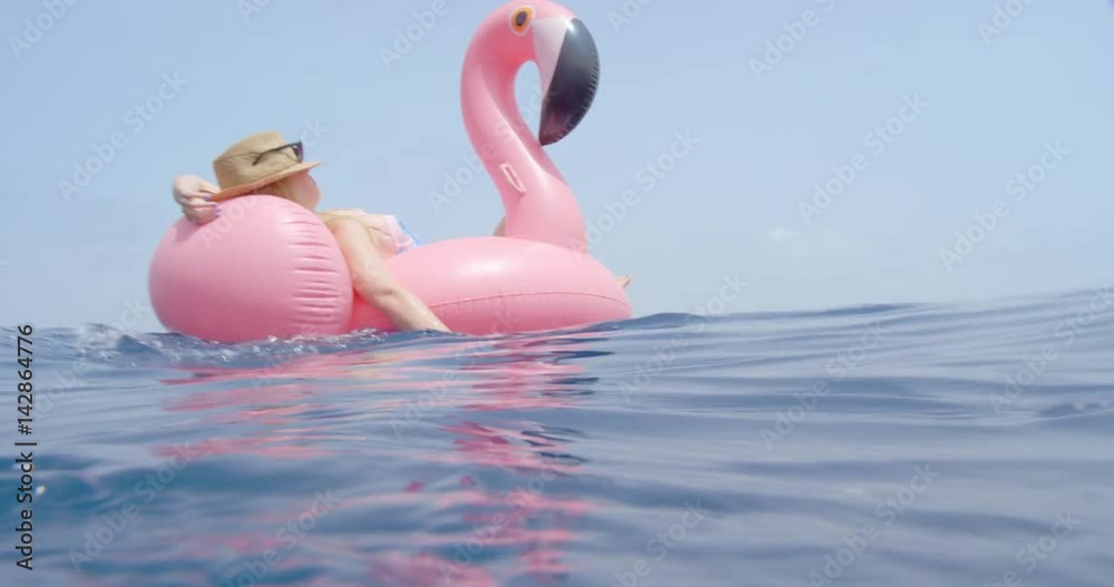 Woman lying on inflatable flamingo floating in middle of ocean girl relaxing in summer sunshine enjoying tropical vacation