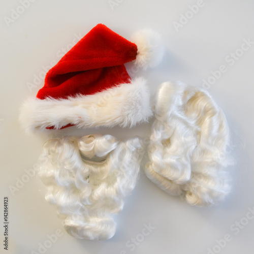 A Santa Clause costume consisting of a beard, wig and hat on a white background