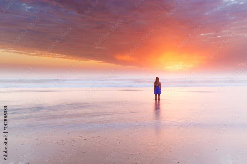 A silhouetted woman watches a beautiful sunrise over the ocean on Australia. A silhouetted woman watches a beautiful sunrise over the ocean on Australia.