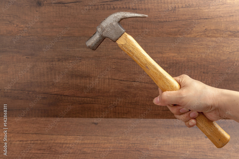 man handle a hammer on wooden background.