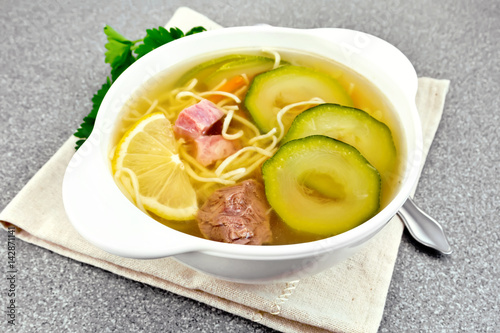 Soup with zucchini and noodles on stone table