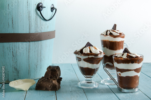 Three chocolate parfaits on a rustic aqua background with wood basket