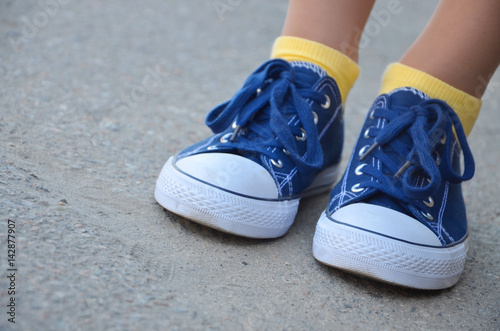 Beautiful legs in blue sneakers and yellow socks © Maisterix