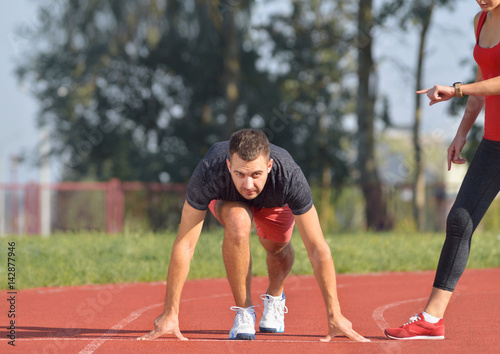 Athletic man on track ready to run. Healthy fitness concept with active lifestyle.