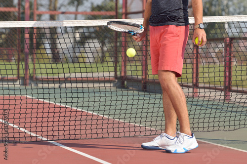Male tennis player with racket ready to serve a tennis ball