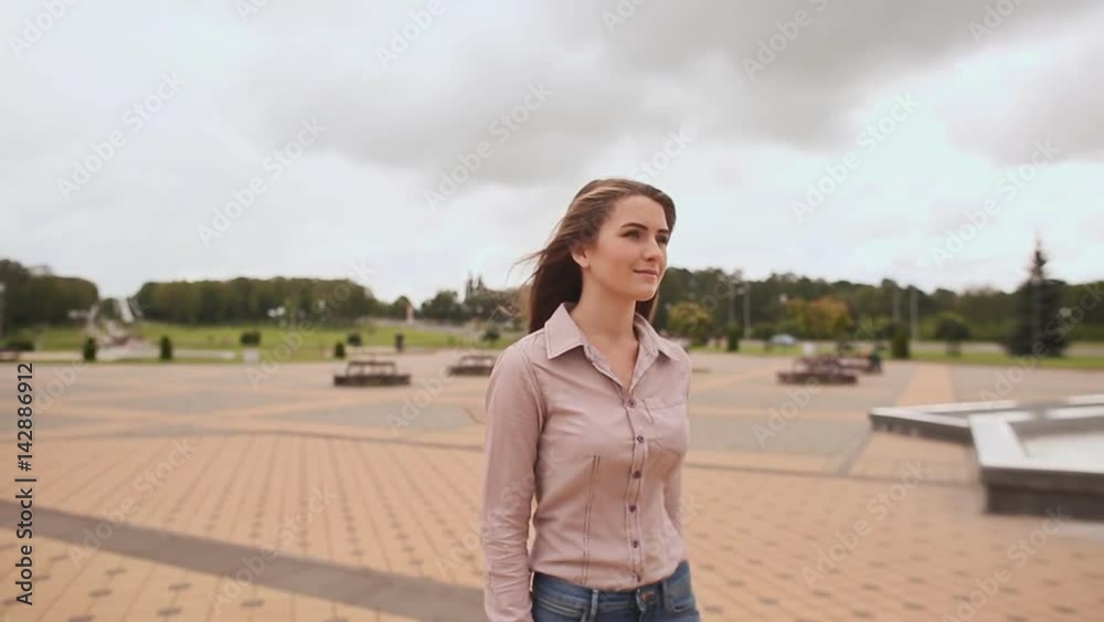 Young girl with long hair in shirt and jeans is in the city park. Young girl with long hair in shirt and jeans is in the city park.