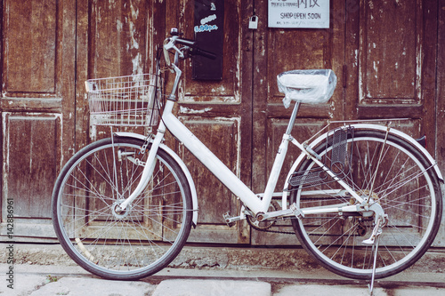 Old bicycle in front of the store in the morning.