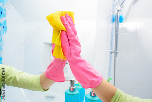 people, housework and housekeeping concept - happy woman cleaning mirror with rag at home