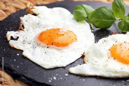 Fotografija fried eggs with basil pepper and salt