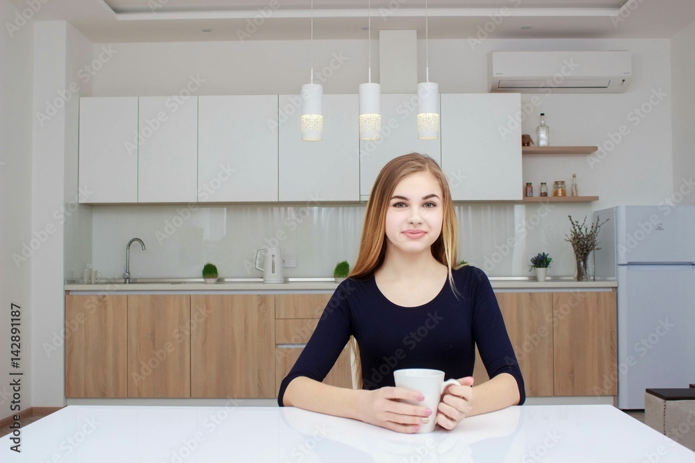 Woman smiling sitting in kitchen with coffee cup. Beautiful girl with long hair. Woman smiling sitting in kitchen with coffee cup. Beautiful girl with long hair.