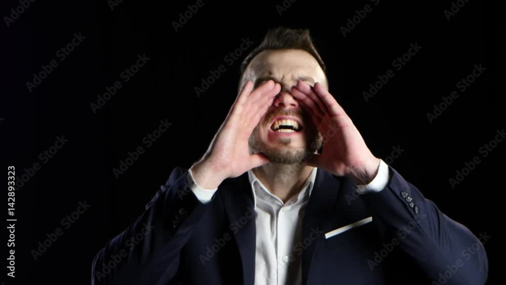 Businessman yells with his hands to his face, black background Businessman yells with his hands to his face, black background