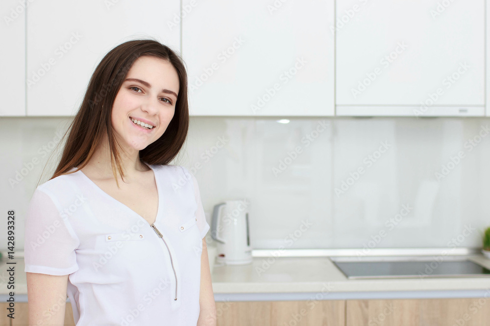 Pretty young woman With black hair standing in kitchen and smiling