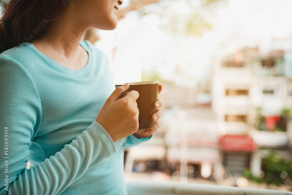 Portrait of a happy asian woman thinking and holding coffee or tea cup at breakfast Portrait of a happy asian woman thinking and holding coffee or tea cup at breakfast