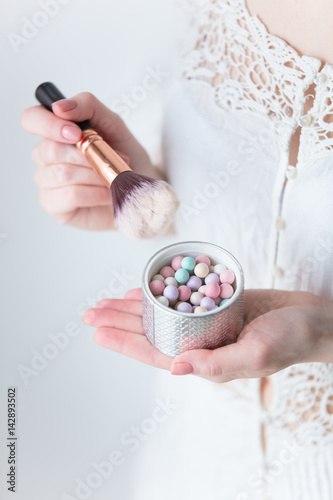 photo of young woman holding powder and brush on the wonderful white background
