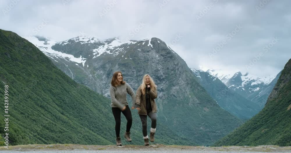 Group of people dancing silly freestyle dance outdoors celebrating hiking at top of snow capped mountain Crazy dancer girl having fun enjoying nature celebrating vacation travel adventure Norway