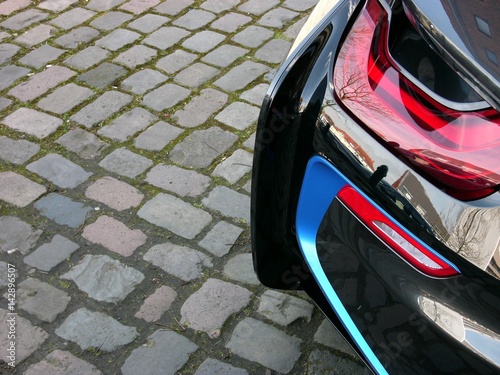 Rotes Rücklicht eines modernen schwarzen Plug-in-Hybrid Sportwagen und Coupé aus Deutschland auf altem Kopfsteinpflaster am Kreativkai am Hafen von Münster in Westfalen im Münsterland photo