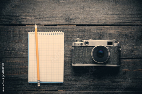 photo of notebook with pencil and retro camera on the wonderful brown wooden background