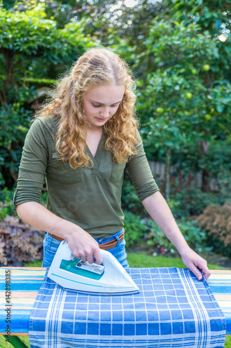 Young dutch woman ironing tea towel outdoors © benschonewille