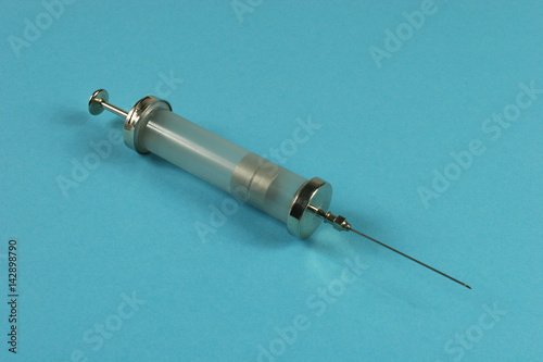 Old injecting syringe on blue background photo