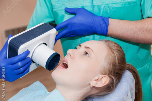 Dentist special device examines a woman's teeth