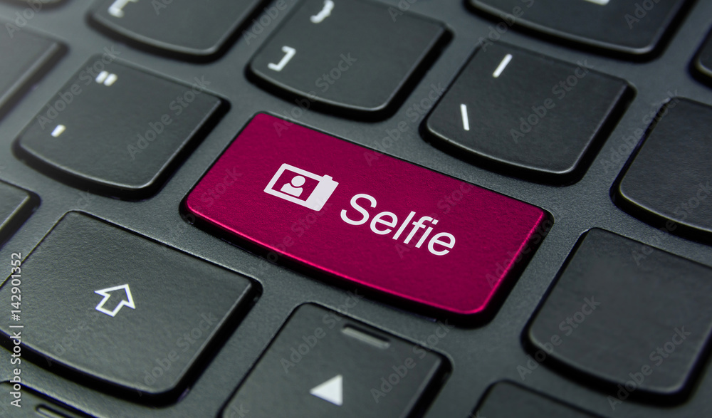 Close-up the Selfie button on the keyboard and have Pink color button isolate black keyboard Close-up the Selfie button on the keyboard and have Pink color button isolate black keyboard