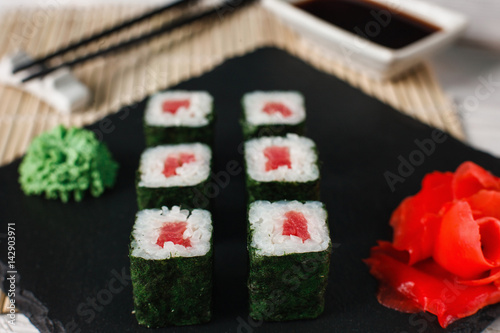 Delicious, fresh and tasty sushi rolls set with tuna served on black slate, close up. Japanese seafood, maki.