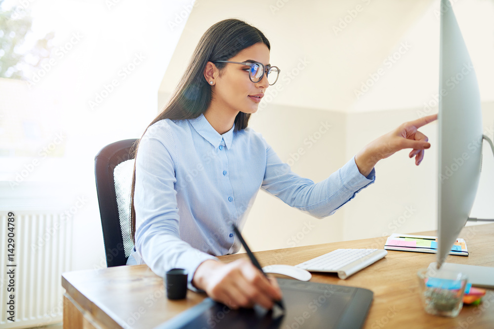 Artist pointing at monitor while working at desk Artist pointing at monitor while working at desk