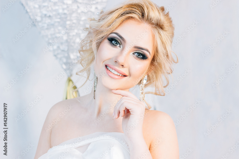 Portrait of a beautiful bride who is holding a wedding dress in a bright room Portrait of a beautiful bride who is holding a wedding dress in a bright room