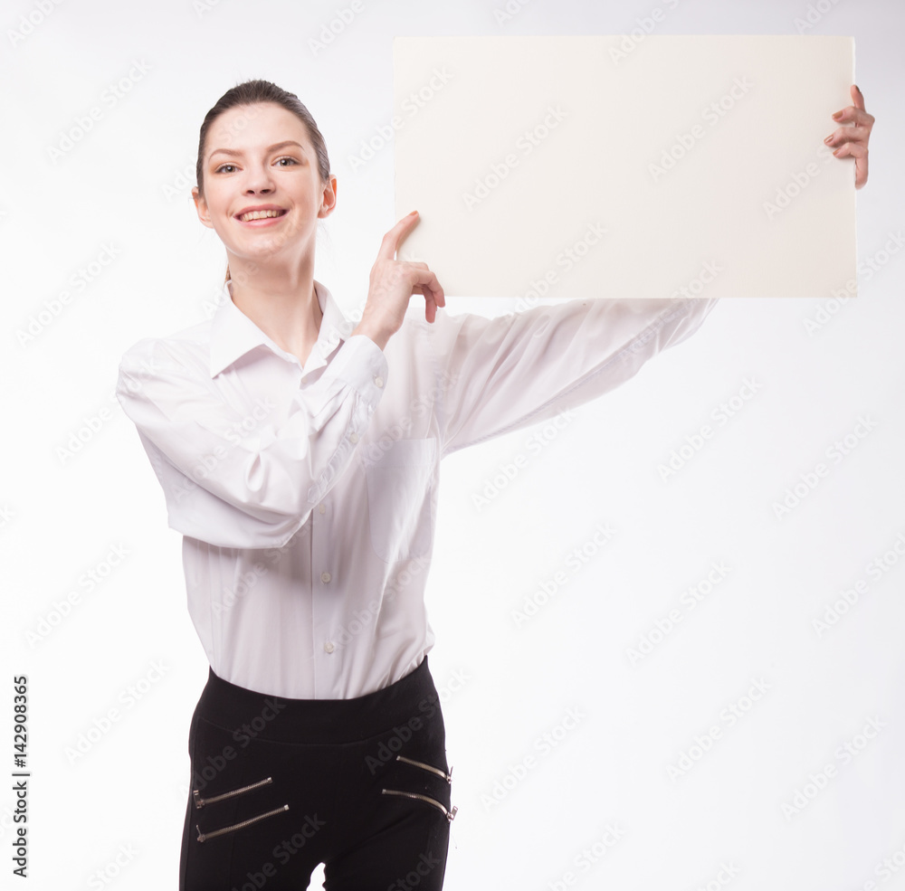Young happy woman showing presentation, pointing on placard over gray background Young happy woman showing presentation, pointing on placard over gray background