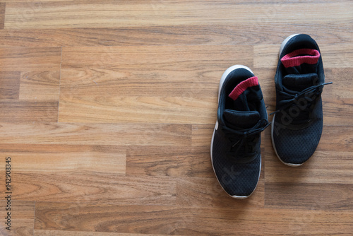 Top view of Black sneaker on the wooden floor.