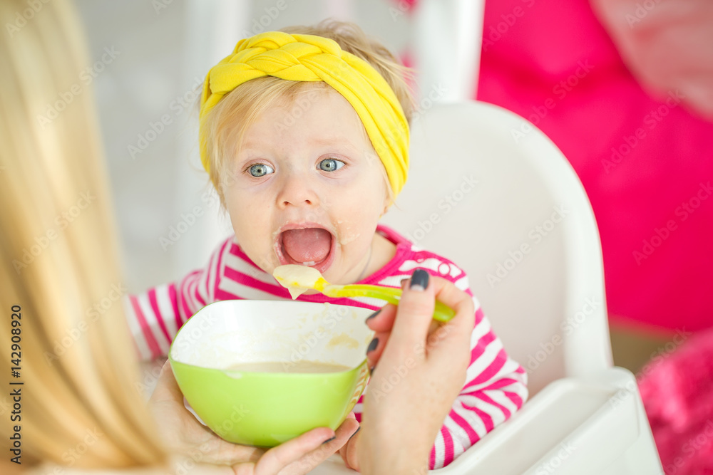 A woman is feeding a young child A woman is feeding a young child