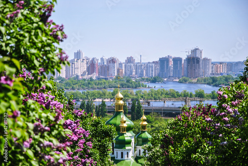 Iconic view to a monastery Vydubitsky and Dnieper River from a botanical garden of Kyiv with blooming lilac, Ukraine.;
