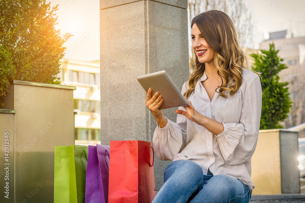 Young woman using digital tablet after shopping Young woman using digital tablet after shopping