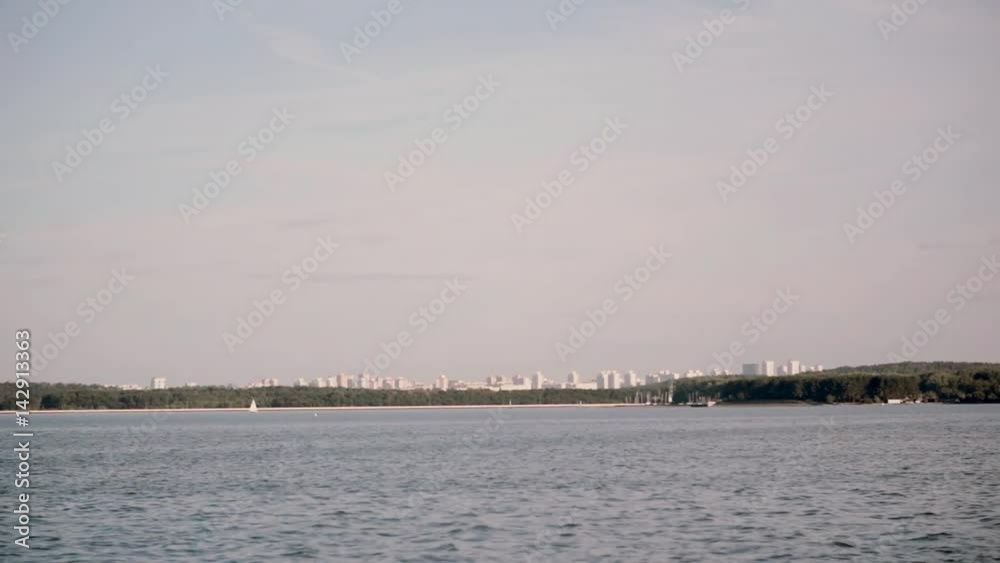 View from the moving ship to the city landscape. Sunny bright day in the open water, lake with blue water scenery. View from the moving ship to the city landscape. Sunny bright day in the open water, lake with blue water scenery.