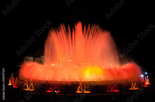 Throngs of people at colourful light & water fountain show. Night at Magic Fountain in Barcelona. Large attraction turns on at night & provides entertainment for all ages on a warm evening.