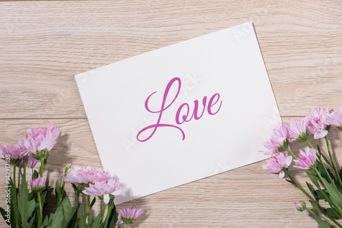 Pink flowers and empty paper for your text on wooden background