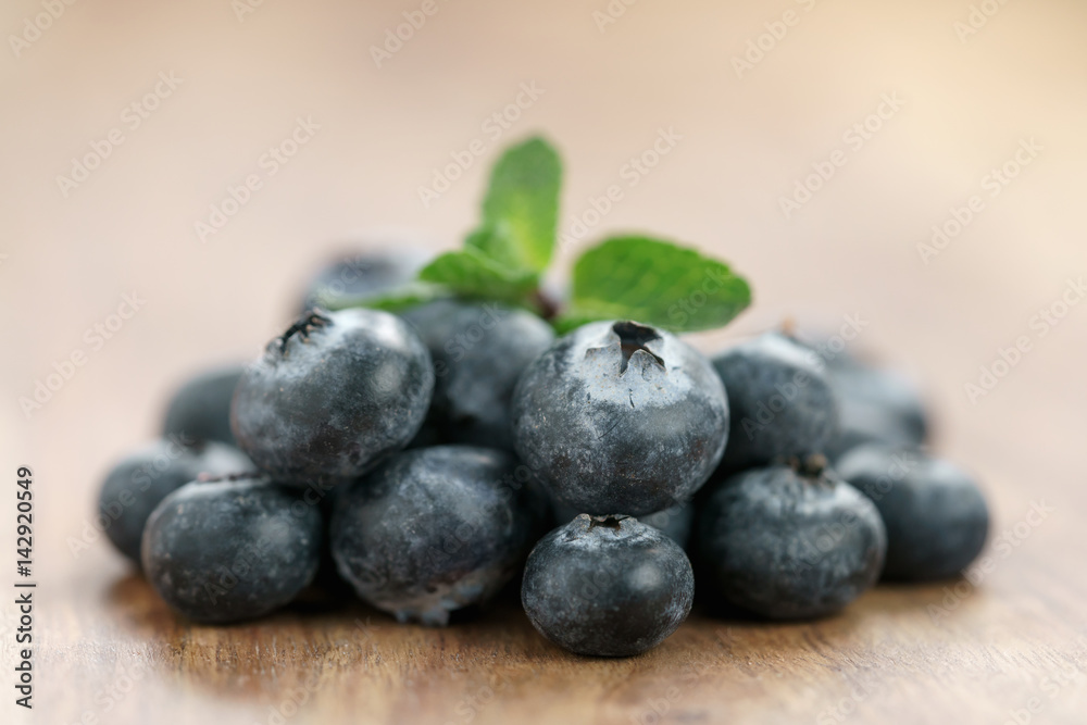 heap of fresh garden blueberries with mint leaves on wood table, closeup photo heap of fresh garden blueberries with mint leaves on wood table, closeup photo