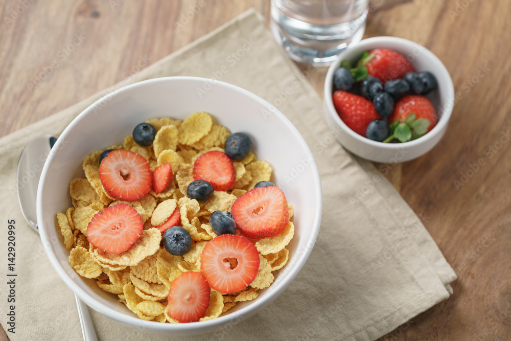 dry corn flakes with berries in bowl on table, breakfast preparation dry corn flakes with berries in bowl on table, breakfast preparation