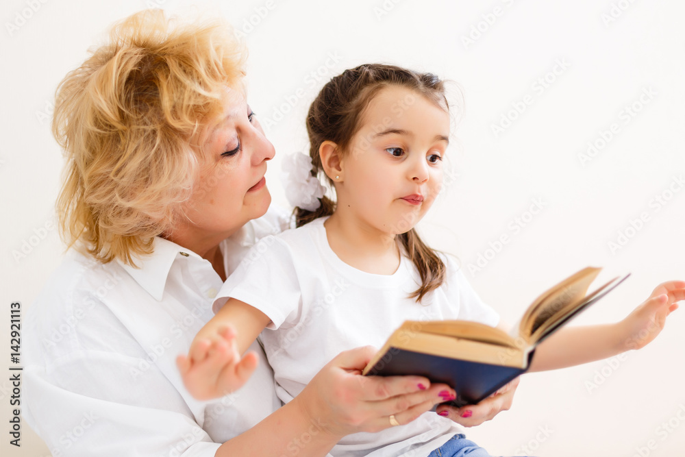 Grandmother teaches to read a book her granddaughter Grandmother teaches to read a book her granddaughter