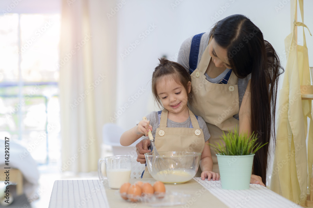 little girl kid making bread by beating fresh egg mixed with milk with mom
