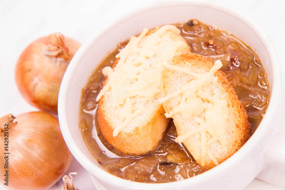 Onion soup with toast on a white background with some onions and garlic