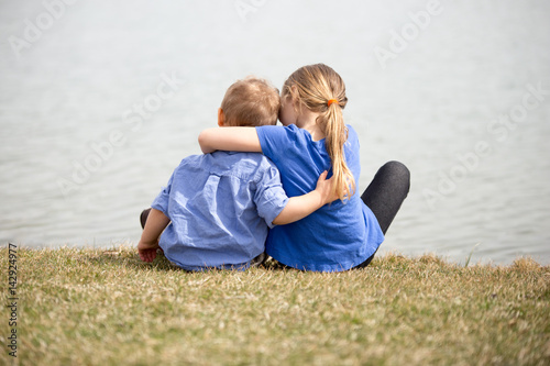 Young sibling boy and girl holding eachothr.