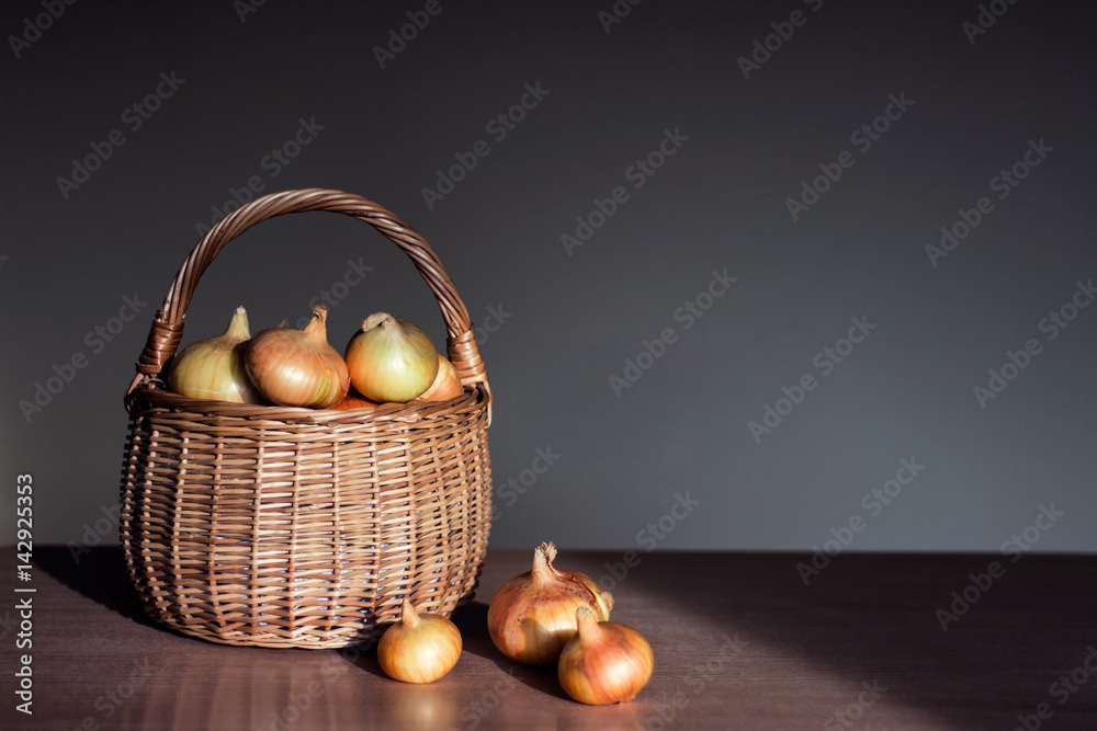 Raw golden onions in a basket on the kitchen table.