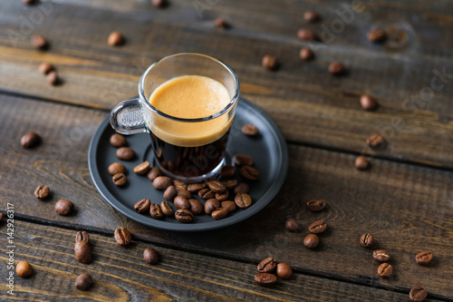A cup of espresso and coffee beans on a wooden table