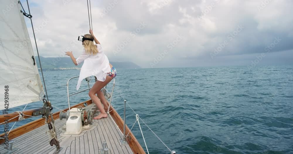 Brave Young Woman at front of sailboat wearing virtual reality headset watching storm 360 video climate change imagination concept Brave Young Woman at front of sailboat wearing virtual reality headset watching storm 360 video climate change imagination concept
