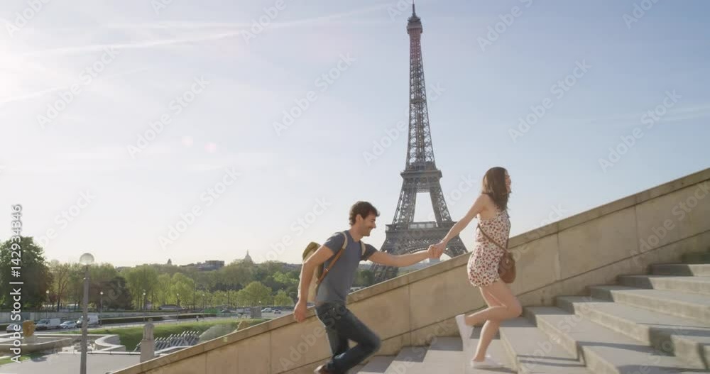 Young couple holding hands woman leading boyfriend walking towards view of Eiffel Tower Paris travel concept