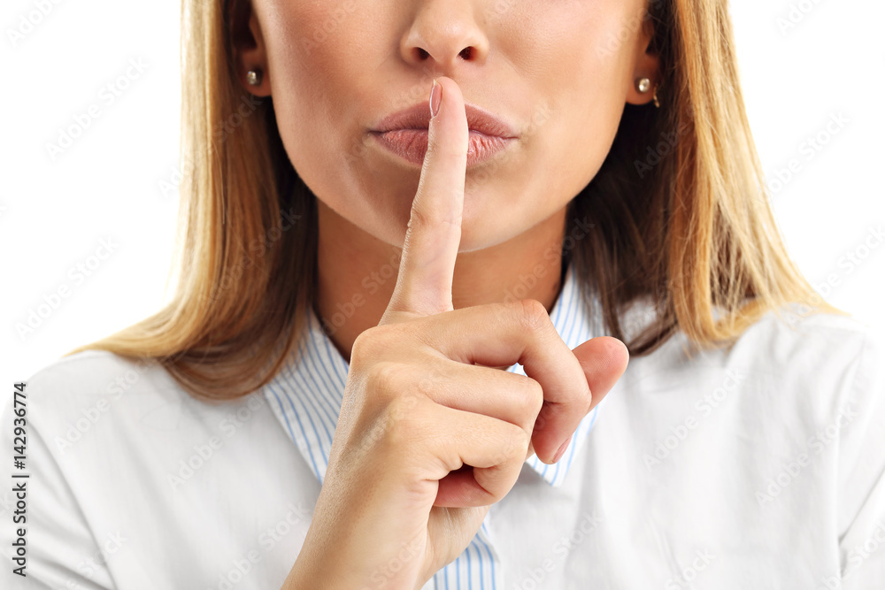 Adult woman holding a finger on her lips over white background Adult woman holding a finger on her lips over white background