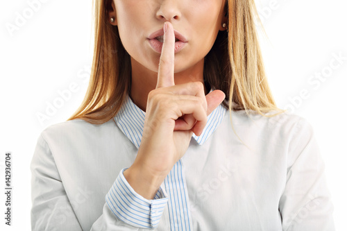 Adult woman holding a finger on her lips over white background