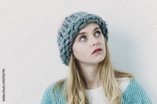 Pretty young girl with blond hair in fashionable sweater, hat